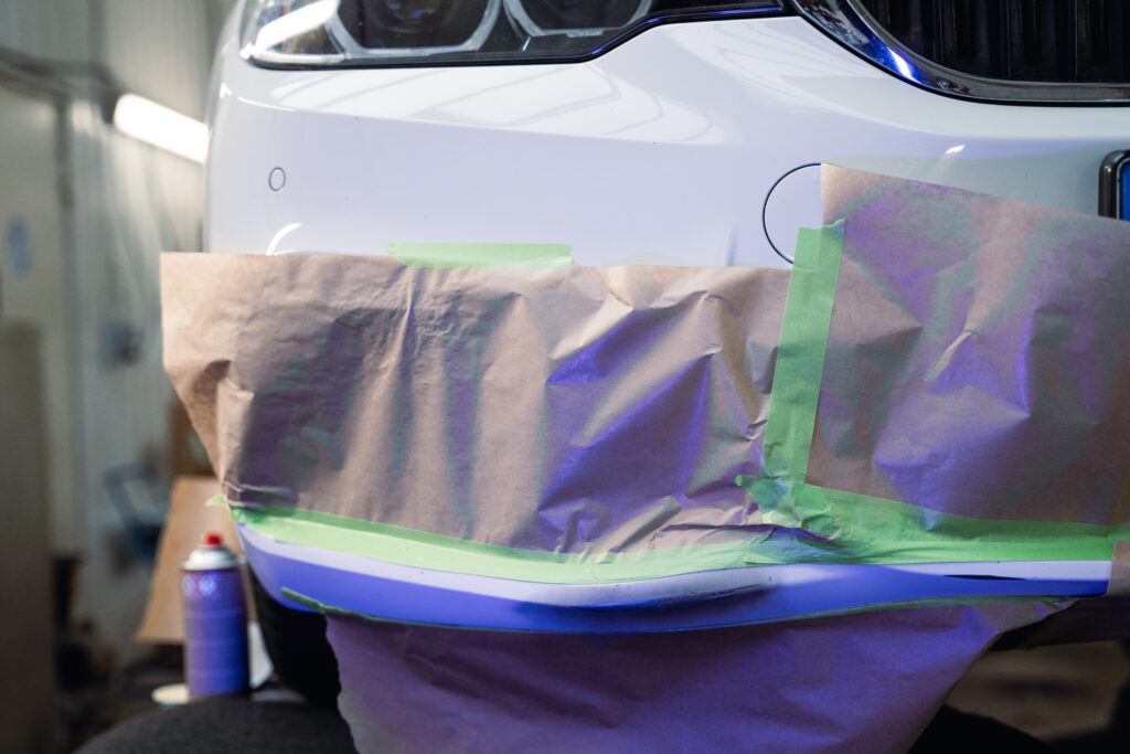 Weißes Auto während Lackinstandsetzung, mit Folie und Werkpapier abgedeckt